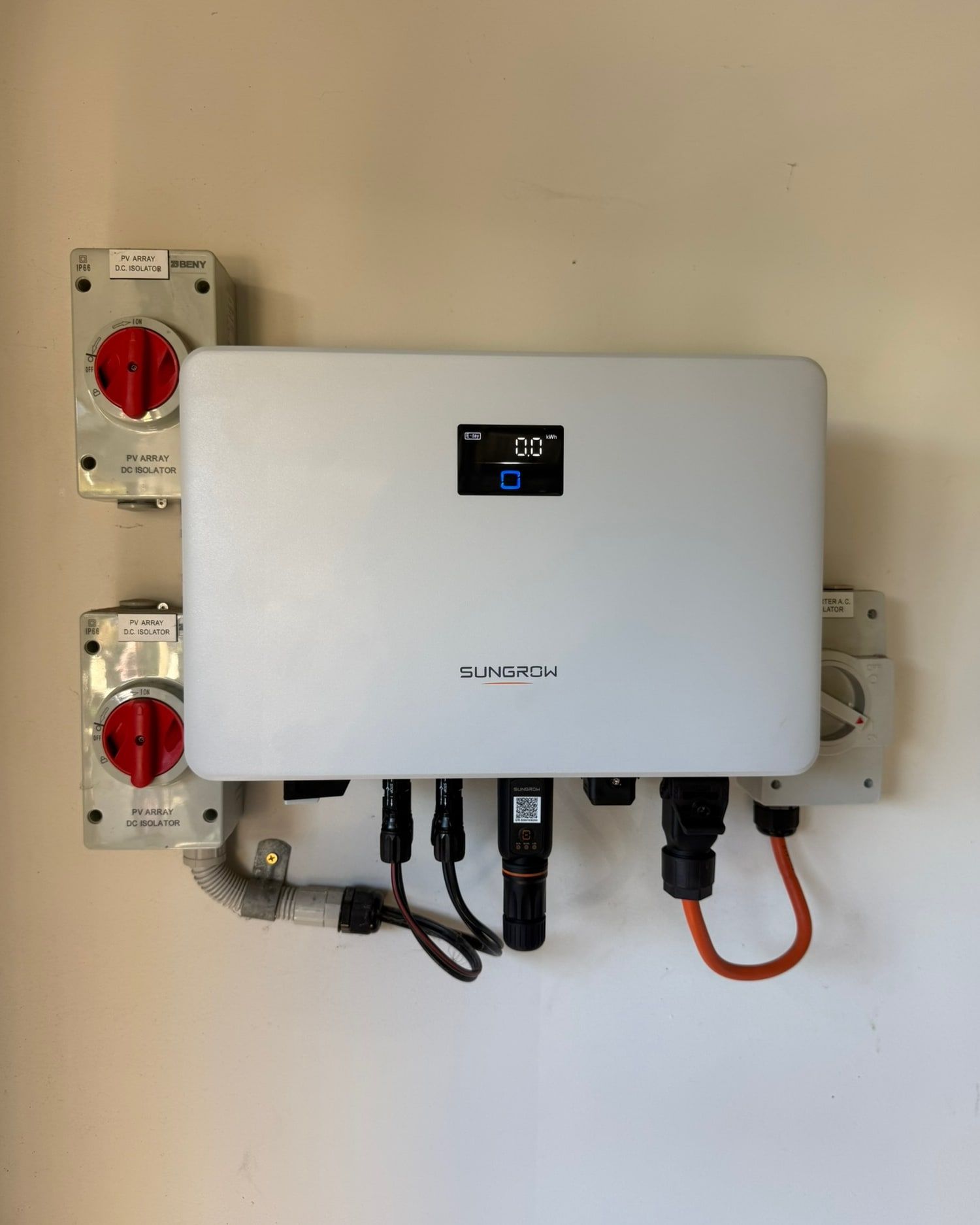 Solar inverter wired to its DC and AC isolators on the wall of a home